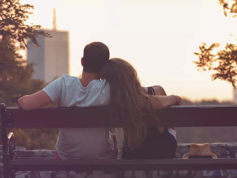 Pareja sentada en un banco de espaldas al atardecer