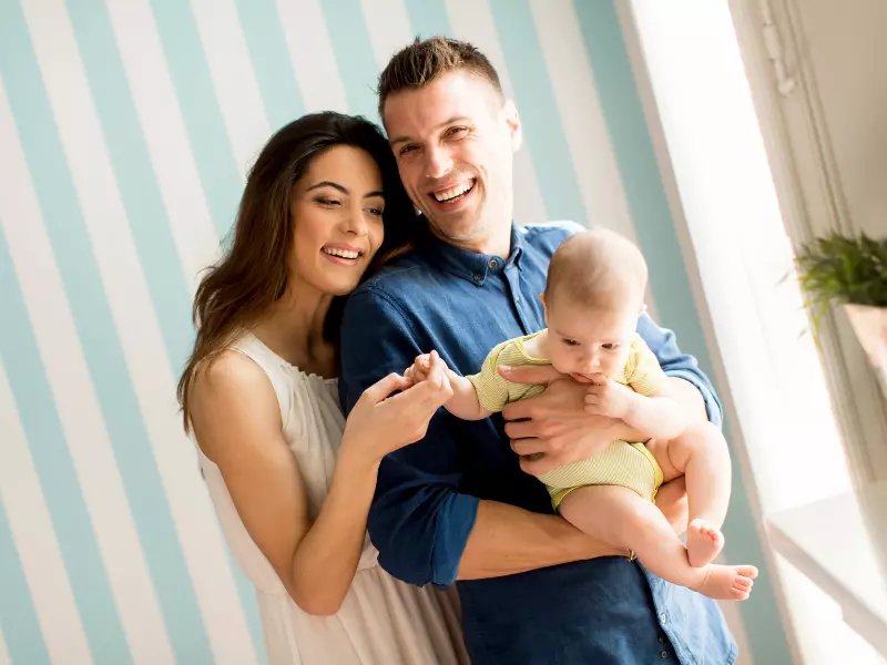 Pareja sujetando a su bebe sonriendo